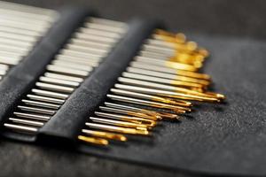uppsättning av guld nålar på en svart bakgrund i en rad. foto