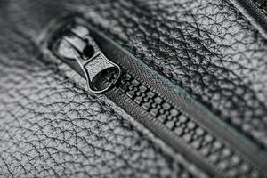 dragkedja reglaget för en svart texturerad läder väska. foto