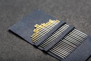 uppsättning av guld nålar på en svart bakgrund i en rad. foto