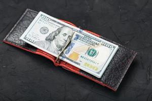 ett hundra dollar i en röd handväska på en svart bakgrund. foto