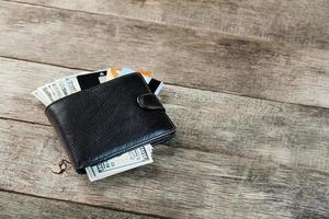 svart plånbok med sedlar, elektronisk kort och bitcoins på en trä- bakgrund. symbol av välstånd och välstånd. foto