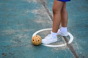 ung sydöst asiatisk kvinna sepak takraw spelare stående nära de bollar i de tjänande Centrum av de domstol, utomhus- sepak takraw spelar efter skola, mjuk och selektiv fokus. foto