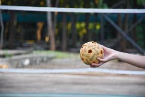 sepak takraw boll, sydöst asiatisk länder traditionell sport, innehav i hand av ung asiatisk kvinna sepak takraw spelare i främre av de netto innan kasta den till annan spelare till sparka över de netto. foto