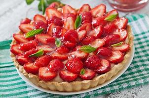 tårta med jordgubbar och vispgrädde dekorerad med myntablad foto