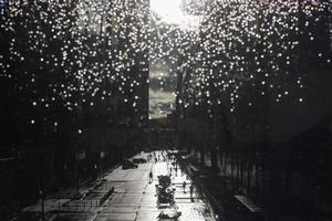 se av de gata av en stor stad med transport och fotgängare genom de glas i regndroppar foto