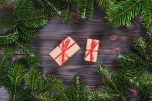 jul presenterar med röd band på mörk trä- bakgrund i en ram tillverkad av gran grenar med käppar. platt lägga stil foto