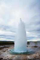 de bra geysir, gejser i sydvästlig Island, haukadalur dal. gejser stänk ut av de jord mot de bakgrund av en molnig himmel foto