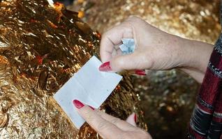 hand av buddist förgyllning guld folder på gyllene boll i tempel foto