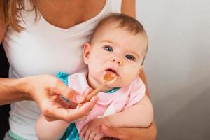 mor matning söt bebis flicka vegetabiliska puré från en sked. friska äter näring för liten barn foto