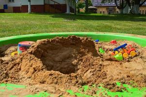 barns sandlåda på de lekplats för spel med leksaker för barn förbi lastbil, bil, grävmaskin, sand byråer med en spatel foto