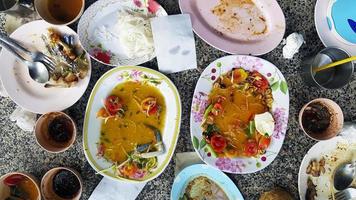 platt lägga av thai mat med kryddad papaya sallad, vit spaghetti, ben kyckling, krabba sallad, sås och färsk tomat förbli på tabell efter äta lunch på restaurang. mat avfall begrepp. foto
