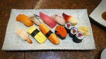 uppsättning av sushi på vit marmor maträtt eller tallrik på japansk restaurang. grupp av färgrik mat och asiatisk mat i japan stil. utsökt måltid med många garnering med skaldjur, fisk, räka, ljuv ägg. foto