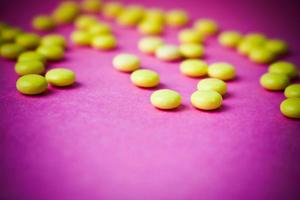 små gul orange skön medicinsk läkemedel runda biljard, vitaminer, läkemedel, antibiotika på en rosa lila bakgrund, textur. begrepp medicin, hälsa vård. platt lägga, topp se foto
