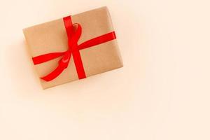 jul gåva låda med röd rosett på beige bakgrund. Semester begrepp, ny år presenterar. foto