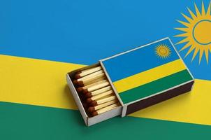 rwanda flagga är visad i ett öppen tändsticksask, som är fylld med tändstickor och lögner på en stor flagga foto