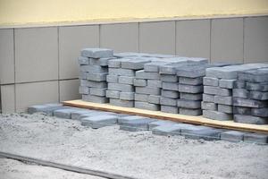 rader av grå och mörk grå gångväg platta liggande utomhus. material för stenläggning plattor förbi mosaik- i framsteg. kullersten installation foto