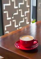 stänga upp röd kaffe kopp med hjärta form latte konst på trä tabell foto