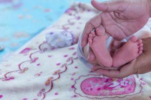 föräldrar händer innehav små nyfödd bebis flicka fötter. foto