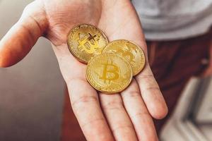 man hand innehav kryptovaluta gyllene bitcoin mynt. elektronisk virtuell pengar för webb bank och internationell nätverk betalning. symbol av crypto virtuell valuta. brytning begrepp. foto