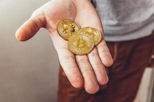 man hand innehav kryptovaluta gyllene bitcoin mynt. elektronisk virtuell pengar för webb bank och internationell nätverk betalning. symbol av crypto virtuell valuta. brytning begrepp. foto