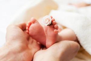 mycket liten fötter. närbild av föräldrar hand innehav mycket liten fötter av liten bebis foto