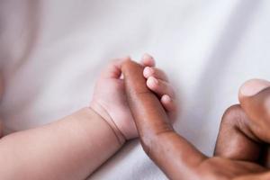 mycket liten hand. närbild av liten bebis innehav fäder finger foto