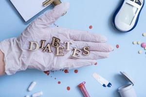 ord diabetes på läkares handskar hand med medicinsk instrument på blå bakgrund foto
