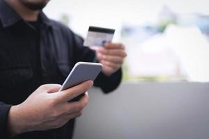 begrepp av uppkopplad betalning via kreditera kort. affärsman användningar en mobil telefon till betala med en kreditera kort genom en bank Ansökan. foto