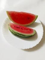 skivad vattenmelon på en tallrik på en vit bakgrund foto