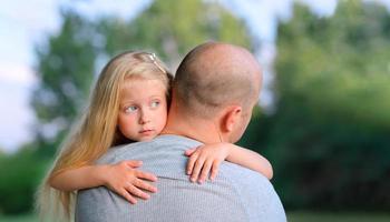 liten blond ledsen dotter kramar sin pappa foto