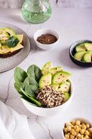 hemlagad skål med avokado, quinoa och spenat på de tabell. friska vitamin näring. vertikal foto