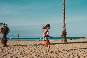 full längd av skön ung kvinna i sporter Kläder joggning medan utövar utomhus foto