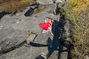 antenn se på flicka i röd klänning liggande på sten eller betong förstörd strukturera foto