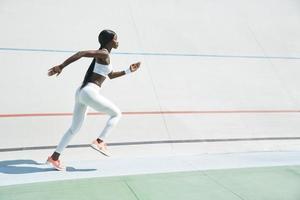 skön ung afrikansk kvinna i sporter Kläder löpning på Spår utomhus foto