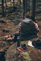 känsla mysigt tillsammans. bak- se av ung par uppvärmningen upp förbi de lägereld medan Sammanträde i de skog foto