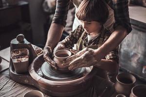 inlärning från självsäker krukmakare. närbild av självsäker liten pojke framställning keramisk pott på de krukmakeri klass foto