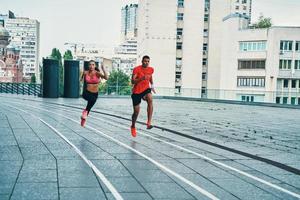 full längd av skön ung kvinna och man i sporter Kläder joggning medan utövar utomhus foto