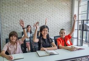 elementärt skola studenter höja deras händer till fråga klass lärare foto