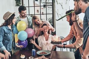 tid till göra en önskar. grupp av Lycklig människor fira födelsedag bland vänner och leende medan har en middag fest foto