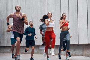 grupp av ung människor i sporter Kläder joggning medan utövar utomhus foto
