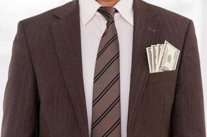 skadad affärsman. närbild av affärsman i formell klädsel med pengar stretching ut av hans ficka foto