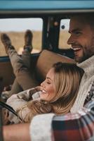 ingenting annan men kärlek. attraktiv ung kvinna vilar och leende medan henne pojkvän körning retro stil mini skåpbil foto