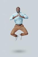 lekfull ung afrikansk man gestikulerar och skrikande medan svävande mot grå bakgrund foto