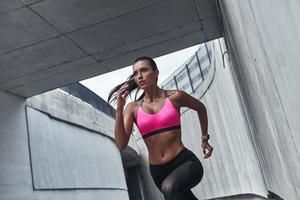 mot en friskare livsstil. modern ung kvinna i sporter Kläder löpning medan utövar utomhus foto