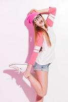 modern tonåring. lekfull ung kvinna i rosa huvudbonader och glasögon Framställ mot vit bakgrund foto