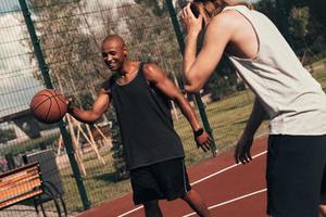 alltid i en bra form. två ung män i sporter Kläder spelar basketboll medan utgifterna tid utomhus foto