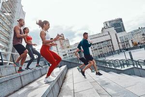 grupp av ung människor i sporter Kläder joggning medan utövar på de trappa utomhus foto