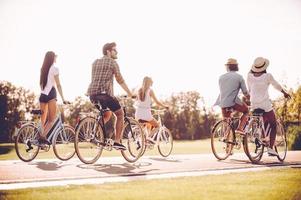 bara en väg ett huvud. grupp av ung glad människor ridning cyklar längs en väg foto