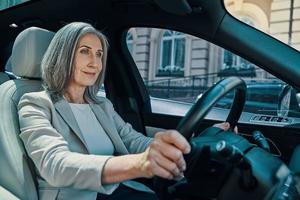 mogna skön kvinna i smart tillfällig ha på sig leende medan körning bil foto