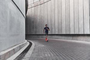starkare och snabbare. full längd av ung man i sporter Kläder löpning medan utövar utanför foto